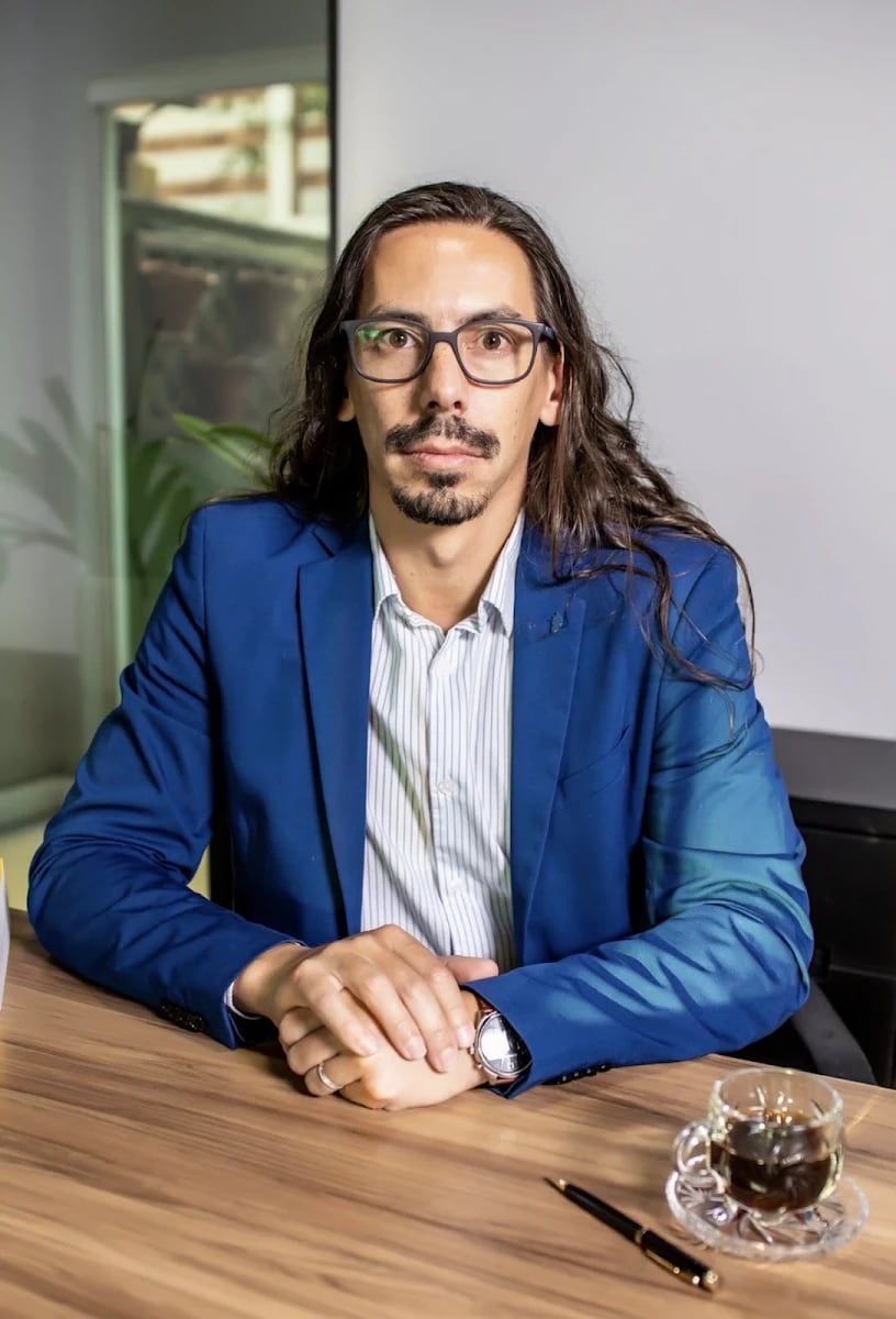 Tiago Bertote sentado à mesa de trabalho no escritório